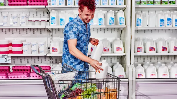 Person in grocery store grabbing milk from shelf