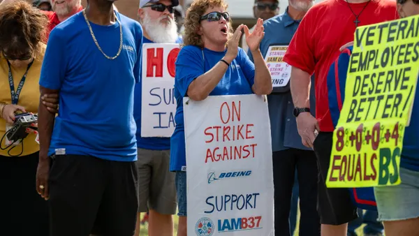 A group of people in blue shirts hold signs that say "Strike against Boeing."