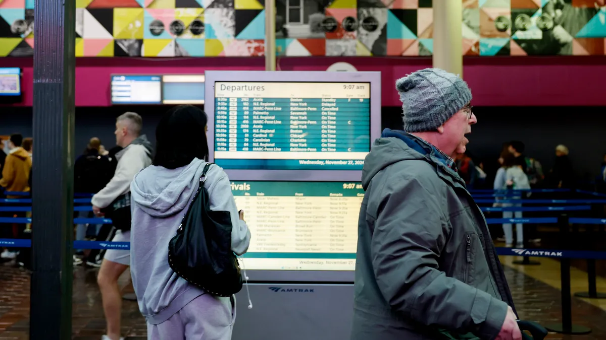 People walking and looking at a "Departures" board.