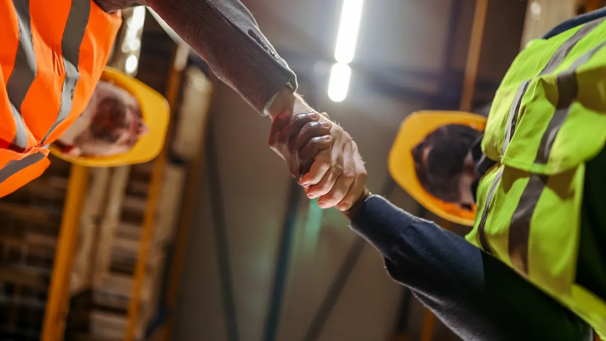Two construction workers shake hands.
