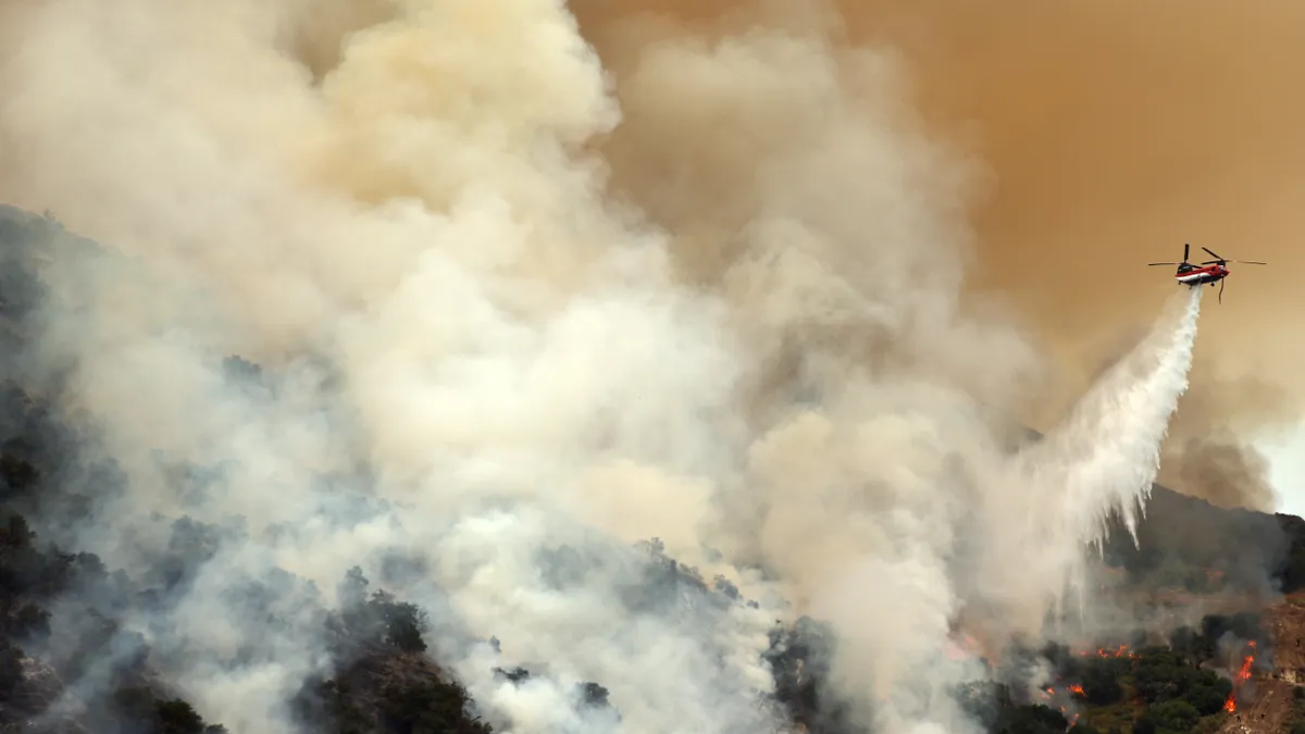 A firefighting helicopter drops water over a wildfire in Los Olivos, California on July 6.