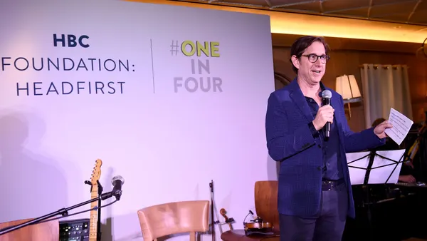 A person holding a document speaks into a microphone.