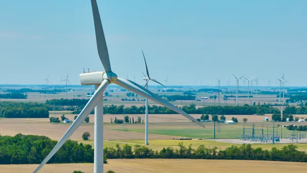 Aerial close up of wind turbine in Ohio with a wind farm and substation in the background.