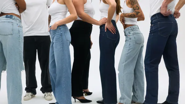 A group of people wearing jeans stand next to each other.