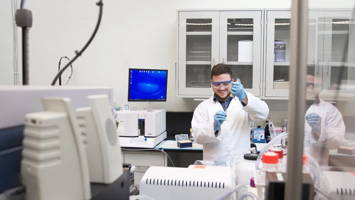 A Cleveland Diagnostics lab technician wearing a white coat and blue gloves analyzes results from an IsoPSA sample in a lab.