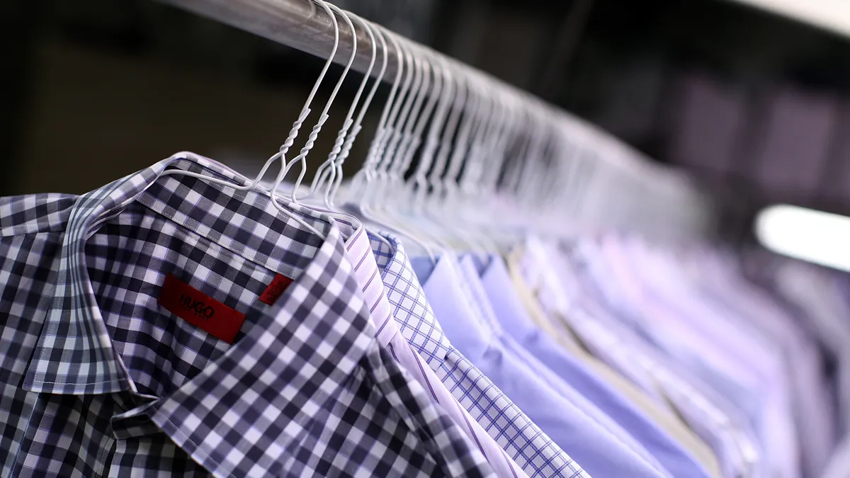 Freshly pressed collared shirts are seen hanging on a rack.