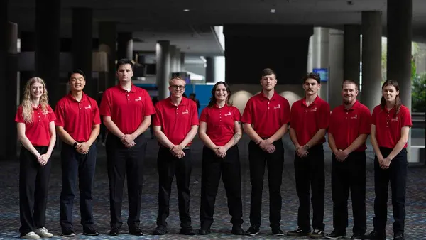 A group of people in matching red shirts pose for a photograph.