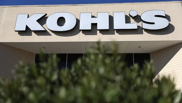 The Kohl's logo store with a view of a green bush.