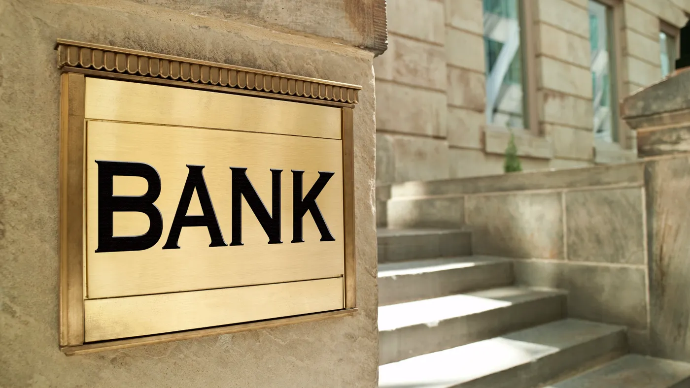 Bank plaque pictured on a city building housing a financial company.