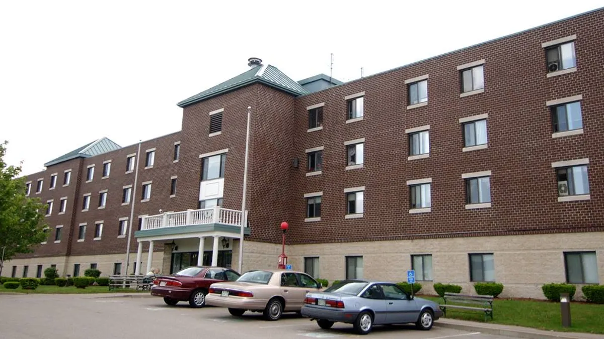 Apartment building with three cars parked in front