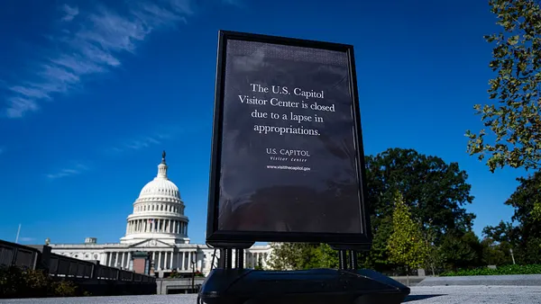A sign notes that the U.S. Capitol Visitor Center is closed due to the government shutdown, with the capitol building in the background.
