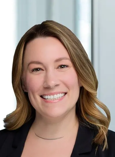 A head and shoulders photo of a person against an office background.