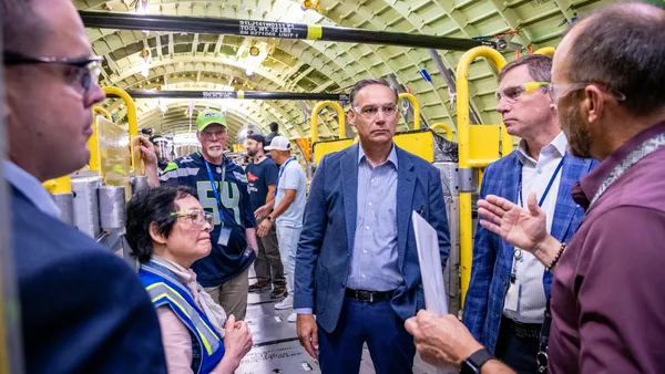 A group of people wearing protective goggles inside a plane factory.