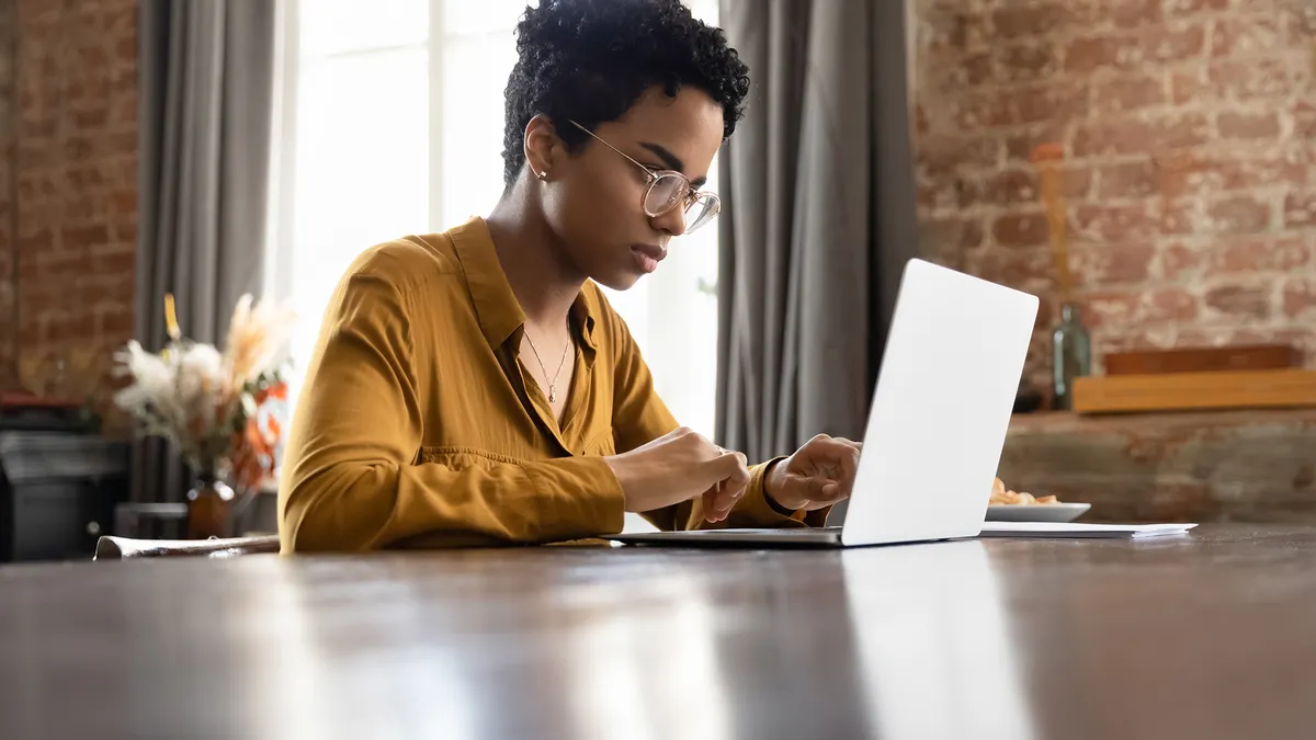 Focused women working on her laptop at the kitchen table