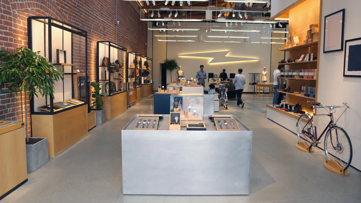 Interior view of a store features one exposed brick wall, a neon art piece of a lightning bolt and various items along the walls on display.