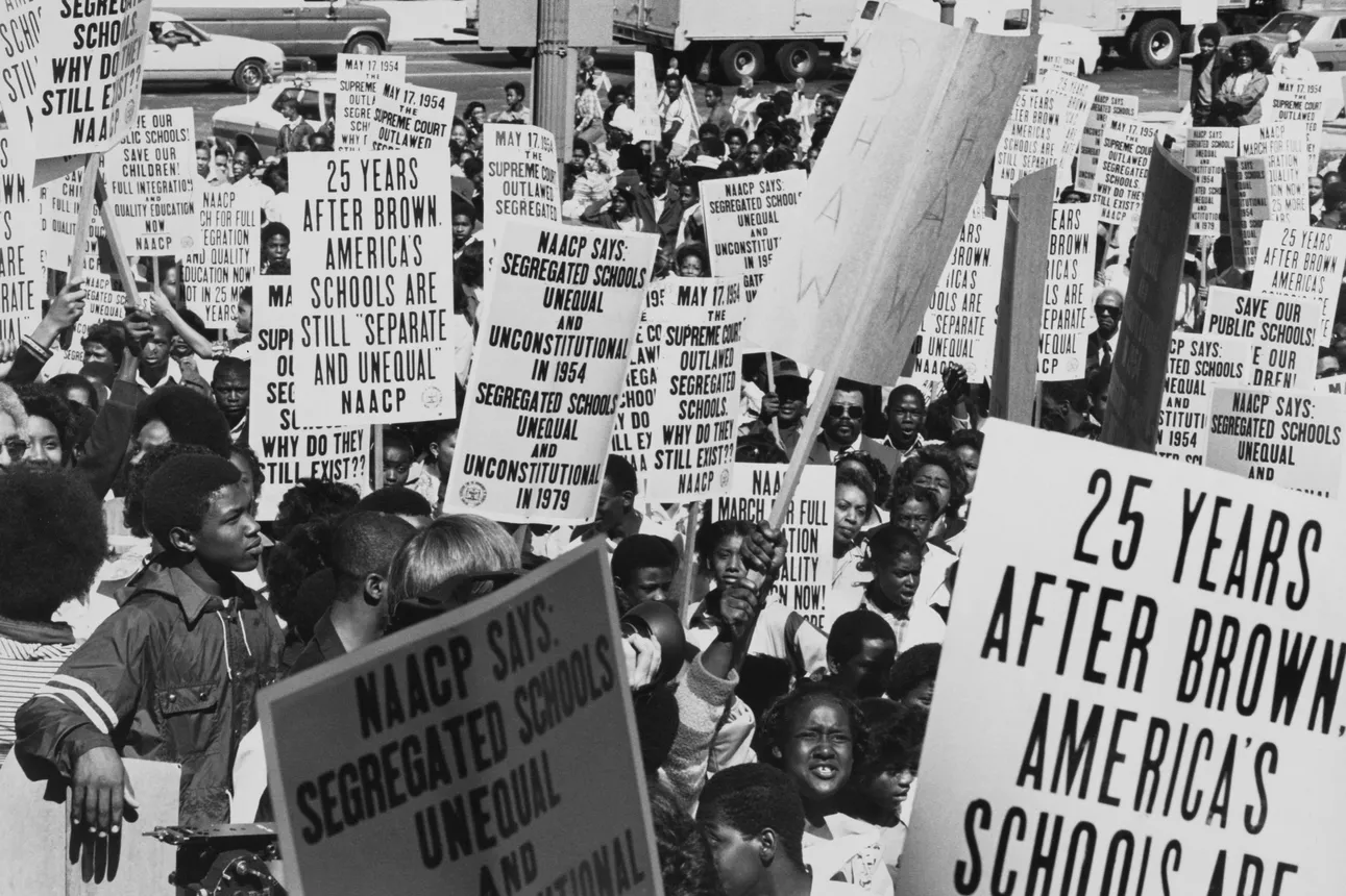 A crowd of Black protestors hold signs