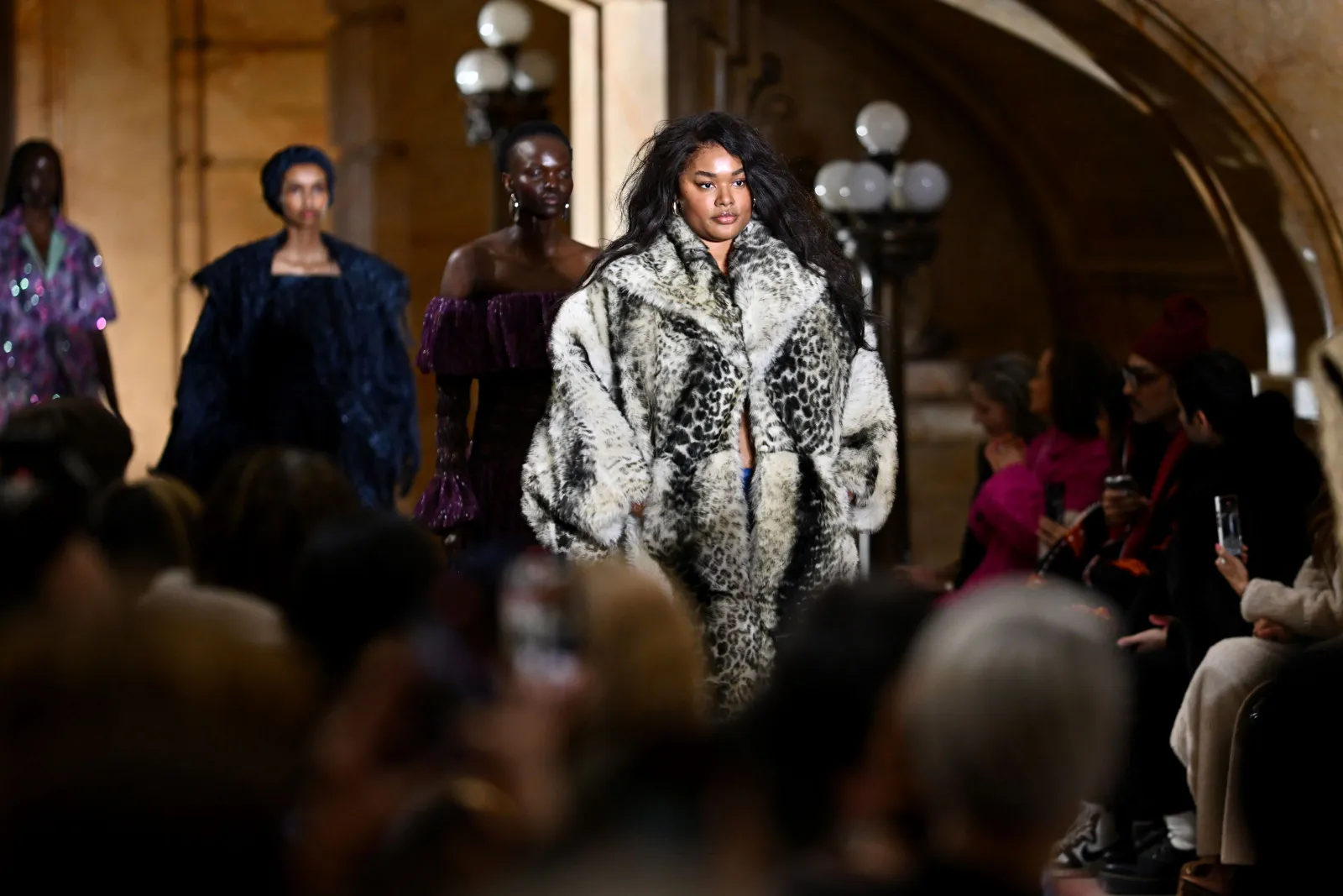 A model in a large fur coat walks down the runway.