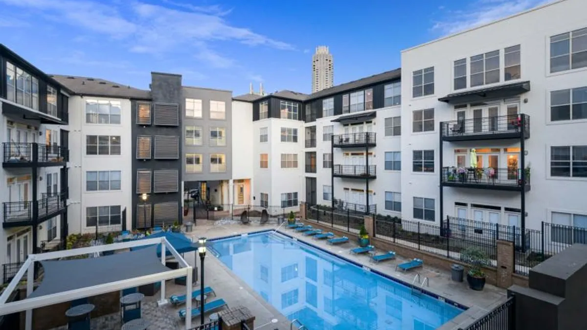 White and black apartment building with a surface-level pool in the foreground.