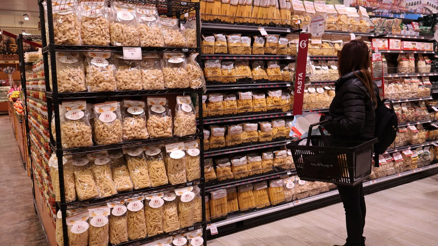 Woman standing in front of a dried pasta display at the grocery store