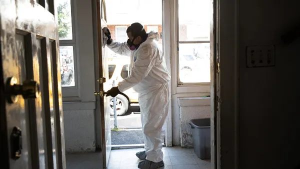 A cleaning technician wearing PPE deep cleans a home.