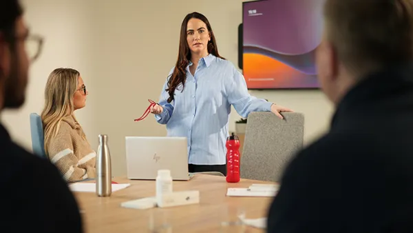 Person standing up and speaking to a board room full of people.