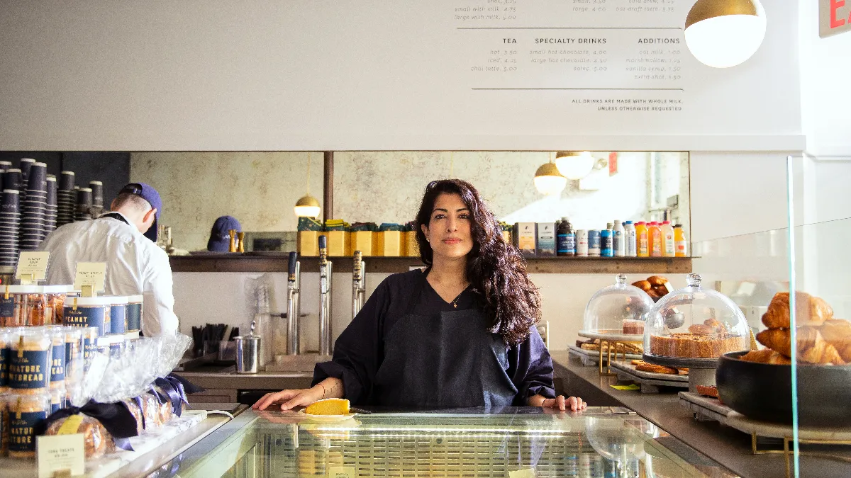 A picture of a woman standing inside a bakery.