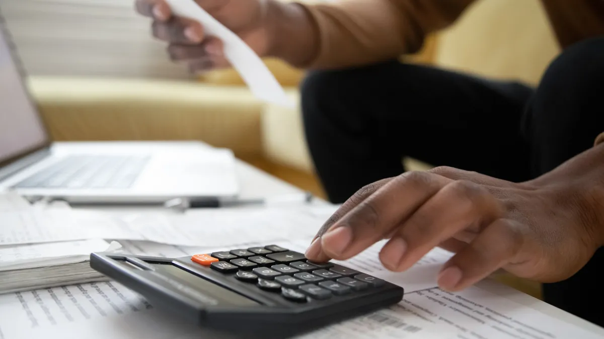 a hand with calculator and papers