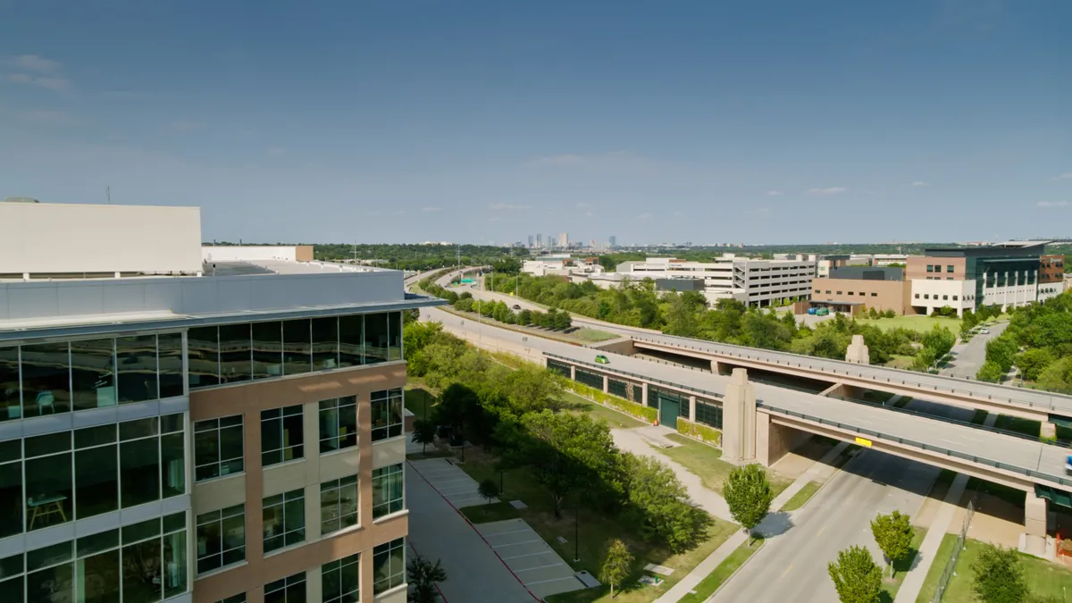 A suburban office building, with a highway and more buildings behind.