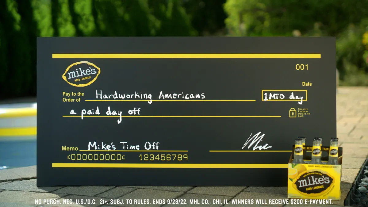 A fake check in black and yellow in front of a pool from Mike's Hard Lemonade.