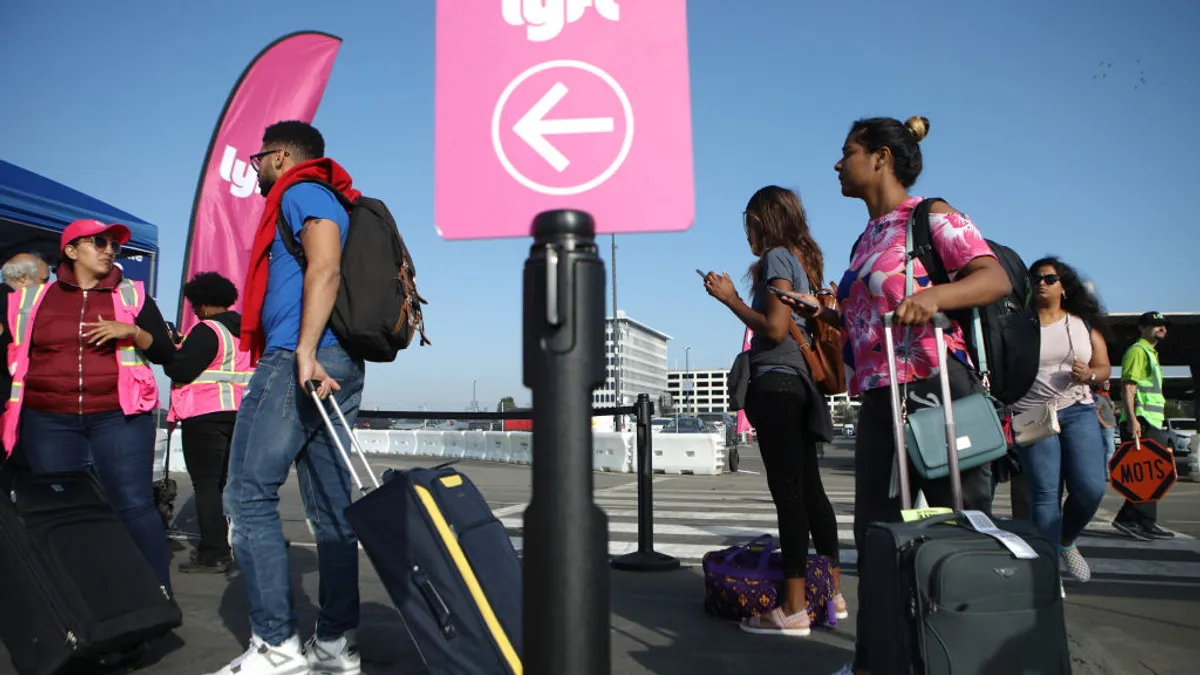 Arriving airport passengers wait to board Lyft vehicles.