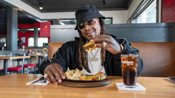 A person sits at a table in a restaurant and holds up a menu item.