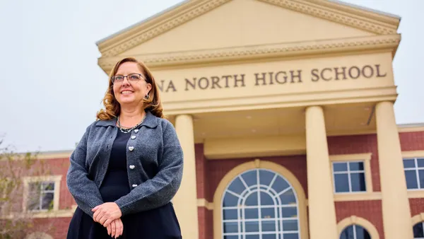 A person stands in front of a building that say "Donna North High School."