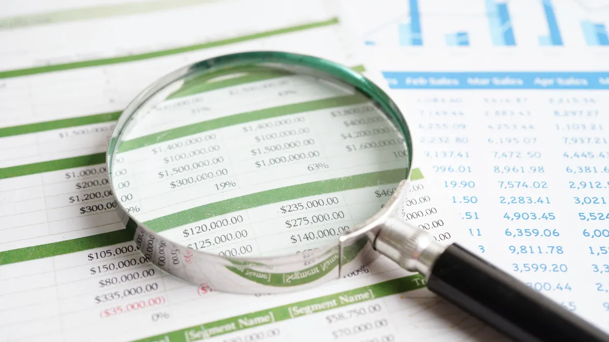A magnifying glass rests on top of a a paper with financial charts on it.