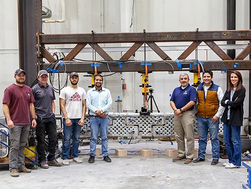 A group of people stand in front of a machine in an indoor industrial setting.