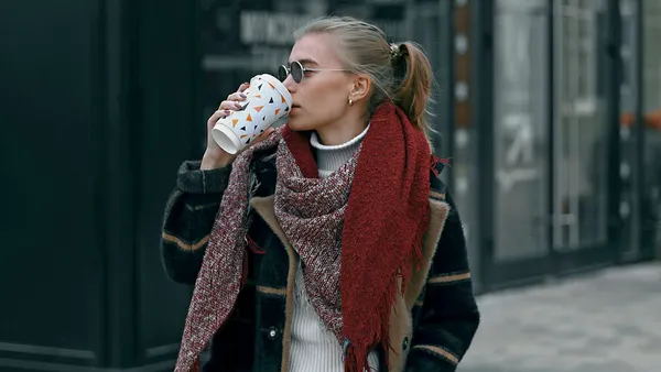 Person walking down street drinking hot drink