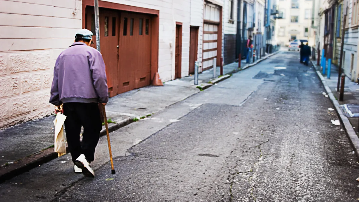 An older adult walking in an alleyway.