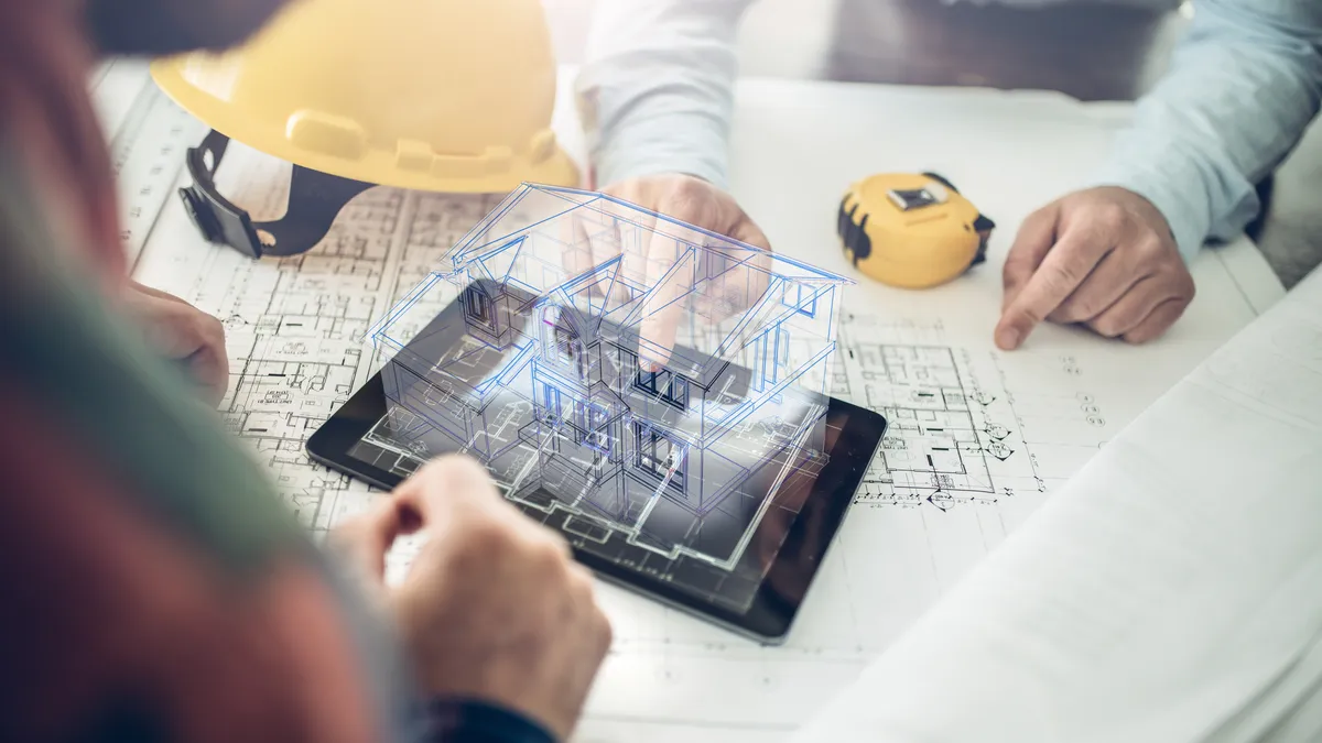 A hologram of a house hovers over a set of construction plans.