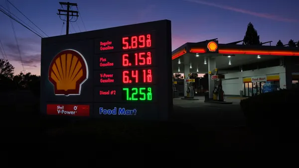 A sign lit up showing prices at a fueling station in California.