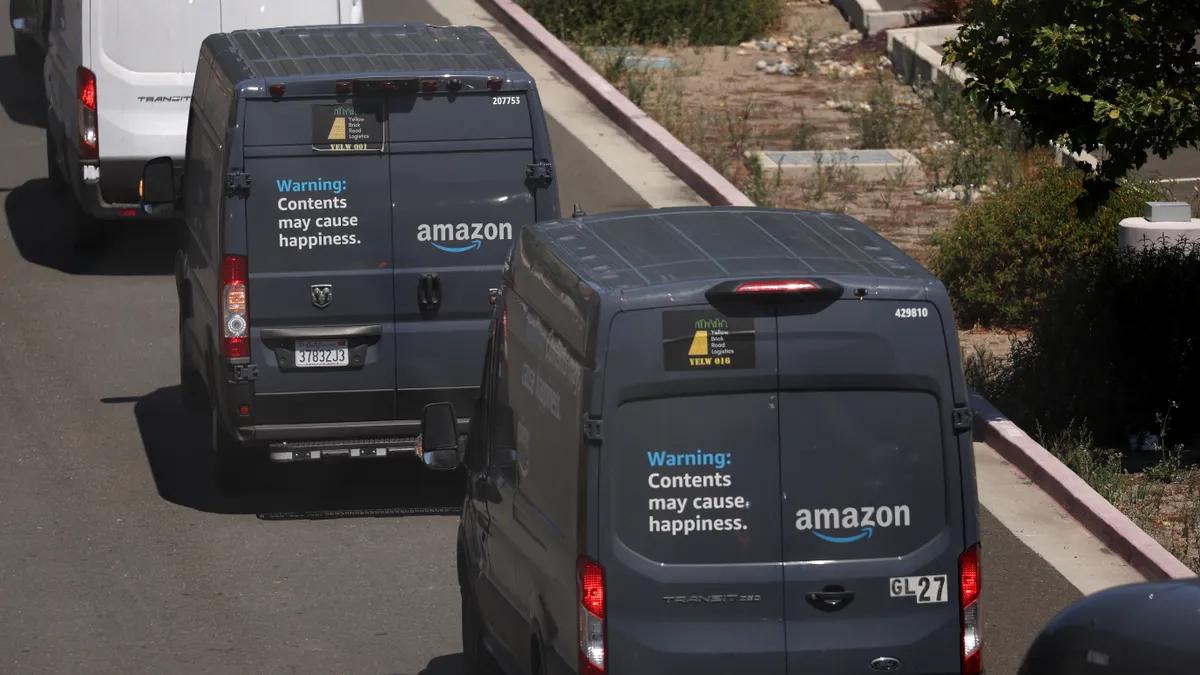 A line of Amazon delivery trucks leave an Amazon distribution facility on June 21, 2023 in Richmond, California.