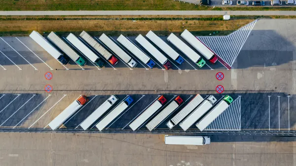 Aerial view of semi-trucks parked diagonally in a lot.
