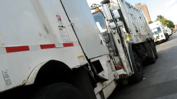 A row of garbage trucks are lined up and parked.