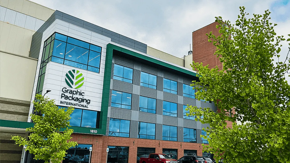 The exterior of a glass and brick industrial facility shows Graphic Packaging International's green and black logo.
