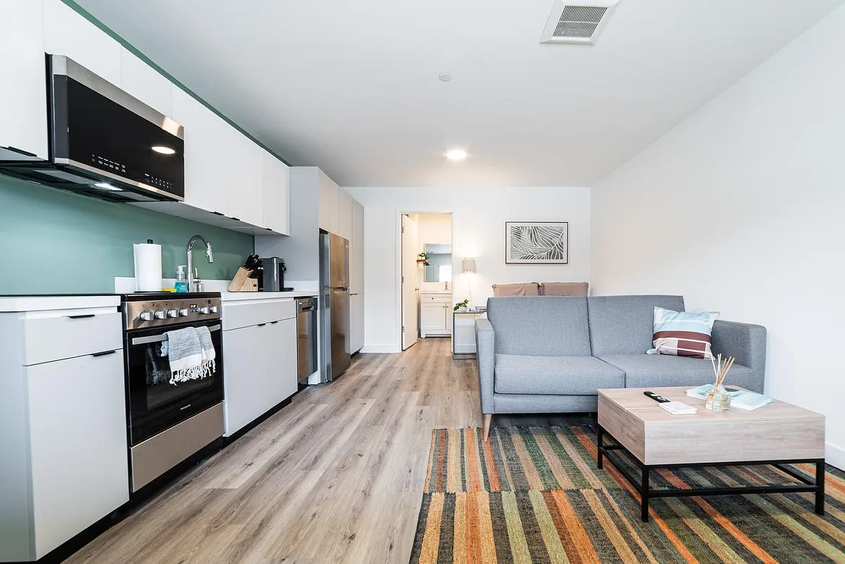 An apartment with a kitchen next to a bed and a sofa.