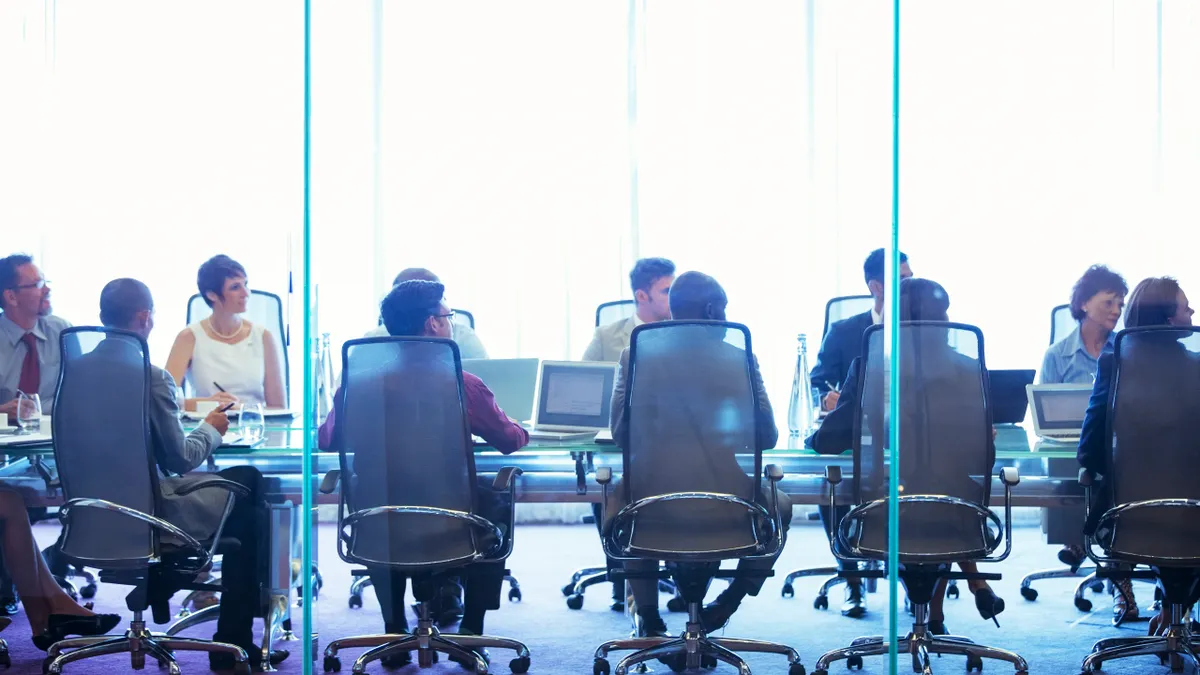 Business people having meeting in conference room, sitting with laptops and discussing