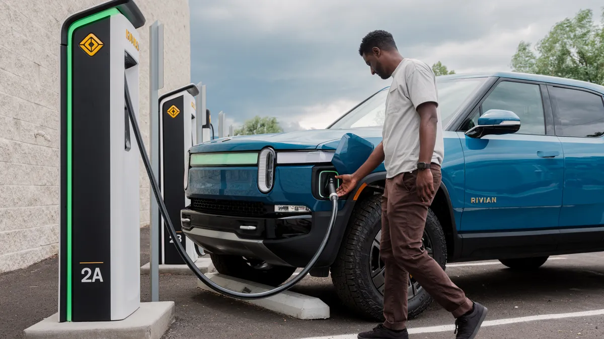 Person plugging a Rivian R1T vehicle into a charger.