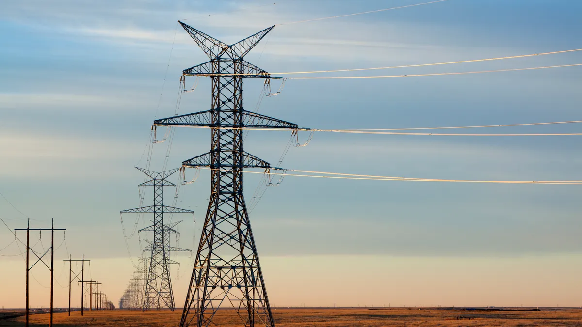 Two rows of power lines in the golden evening light with a soft gentle prairie sky with light cloud cover.