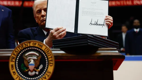 Donald Trump holds up papers with his signature.