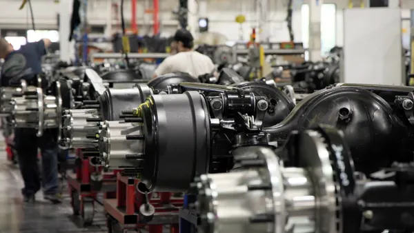 Truck equipment manufacturing with Daimler workers in the background.