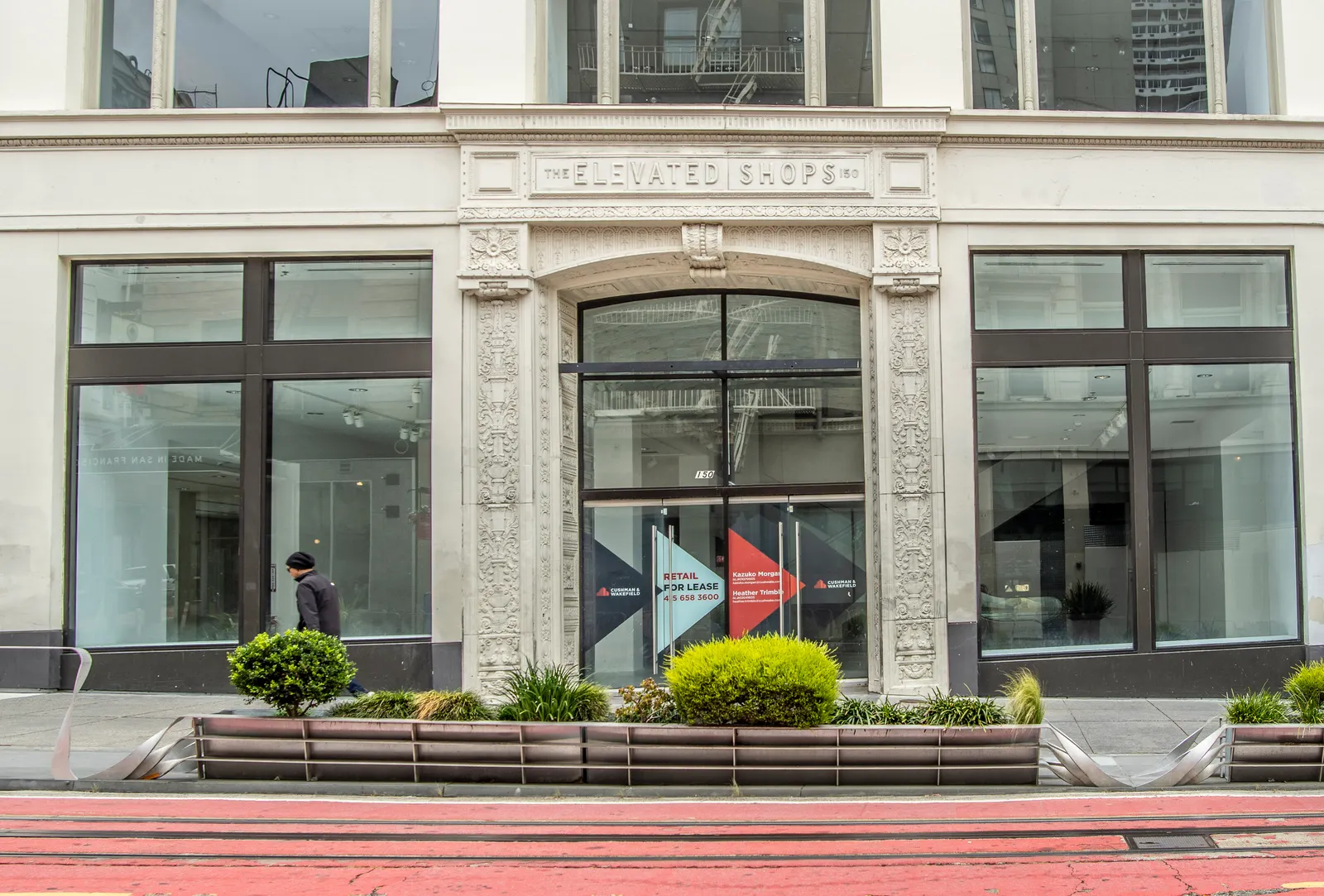 A person walks passed a building for lease.
