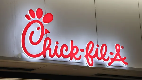 A red sign that says Chick-fil-A on a white wall.